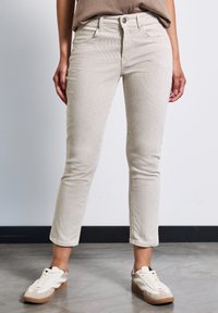 Pantalones de pana beige con rayas verticales, corte slim, de longitud hasta el tobillo, con cierre frontal de botón y cinco bolsillos.