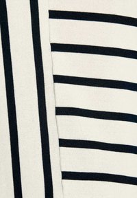 Zwart-witte gestreepte stof met afwisselend dikke en dunne strepen, met een zachte textuur en een gladde breiselontwerp.