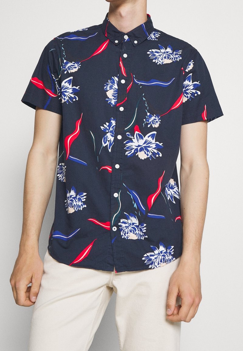 Camisa de manga corta de color navy con estampado floral en blanco y rojo, con cuello abotonado y tejido transpirable de corte relajado.