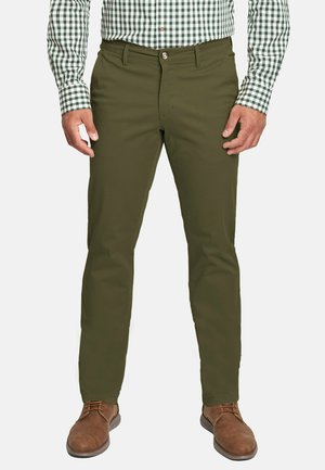 Pantalones verde olivo de tejido suave, con un diseño de pierna recta, bolsillos delanteros y cierre de botón. Llevados con zapatos marrones.