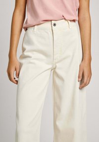 Vita vida byxor i denim med hög midja, med knappstängning fram och subtila sömnadsdetaljer.