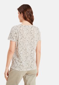 T-shirt met korte mouwen in lichtgrijs met een wit bladerenpatroon, voorzien van een ronde halslijn en een licht gebogen zoom. Zacht, ademend materiaal.