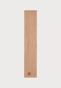 Bufanda de punto acanalado en un cálido color beige, hecha de material suave. Presenta una pequeña etiqueta con el logo marrón de UGG en un extremo.