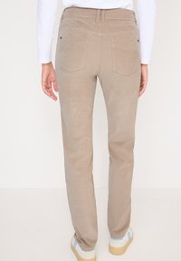 Hnědé kordové kalhoty s rovnými nohavicemi, které mají dvě zadní kapsy a pásek. Látka má jemný, texturovaný povrch.