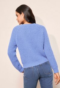 Heledad sinine kudumest svett, millel on tekstuuriline muster, soonilised varrukad ja äär, koos tume siniste teksadega. Seljal vertikaalsed õmblused.