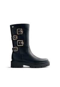 Botas de cuero negro con tres accesorios de hebilla dorada, punta redondeada y una suela gruesa de goma negra texturizada. Acabado suave.