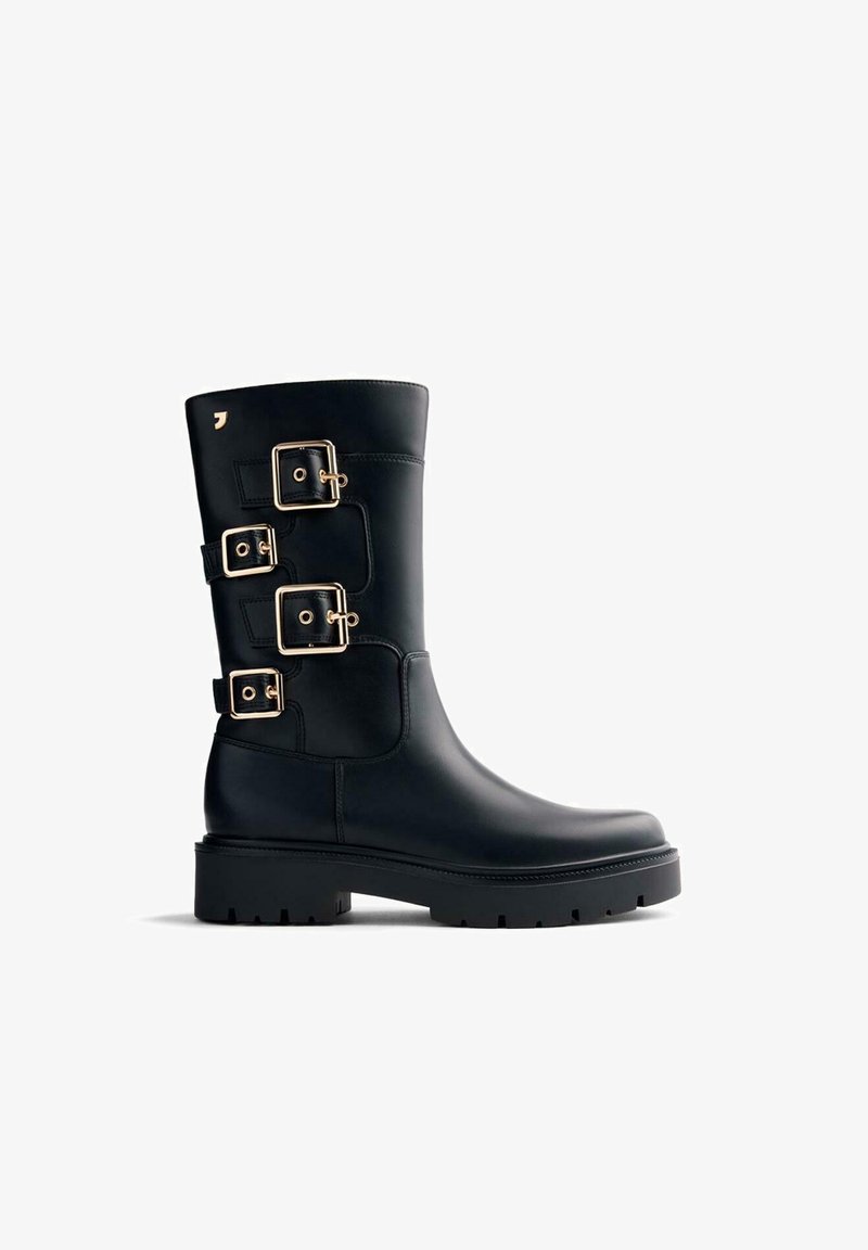 Botas de cuero negro con tres accesorios de hebilla dorada, punta redondeada y una suela gruesa de goma negra texturizada. Acabado suave.