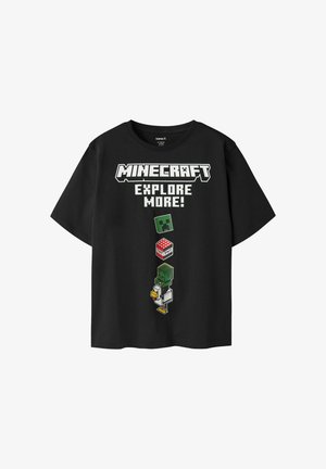 T-shirt noir avec texte Minecraft et personnages pixelisés incluant un visage de Creeper, un bloc de TNT et une silhouette humanoïde tenant un poulet.