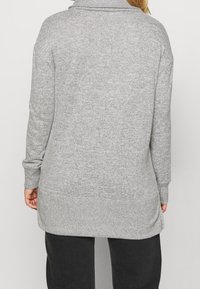 Grauer, langärmeliger Cardigan mit hohem Kragen, gerippten Bündchen und einem leicht verlängerten hinteren Saum. Weiches, strukturiertes Strickmaterial.