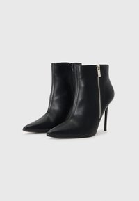 Sorte skinn ankelstøvler med spiss tå, høye stiletthæler og en utvendig glidelåsdetalj på siden. Glatt tekstur, elegant design.