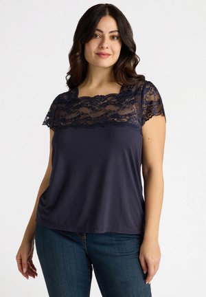 Top navy con maniche corte in pizzo e scollatura in pizzo. Tessuto morbido con una vestibilità comoda, abbinato a jeans di denim.