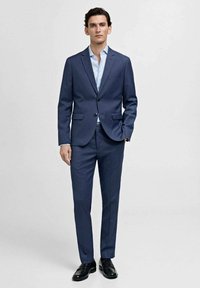 Costum personalizat de culoare bleumarin, cu un singur buton, pantaloni asortați și o cămașă de dress de culoare albastru deschis. Material fin și design elegant.
