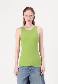 Green ribbed tank top with a round neckline and sleeveless design, paired with loose-fitting blue denim shorts. Smooth texture.
