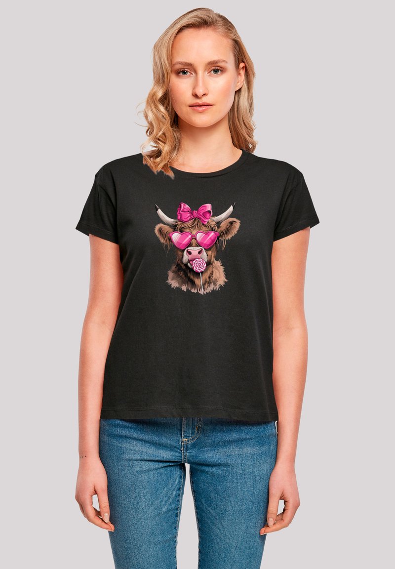 Black short-sleeve t-shirt featuring a graphic of a cartoon cow with pink sunglasses and a bow, printed on a soft, casual fabric.