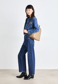 Sötétkék denim dzseki és bőszárú farmer, fekete bőr bokacsizmával és bézs, struktúrált kézi táskával párosítva. Egyszerű, hétköznapi megjelenés.