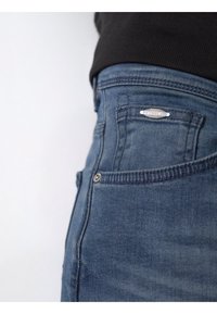 Denimjeans i mörk indigo med en lätt stretch. Har en metall-logotyp på bakfickan och kontrastsytning. Klassisk fem-fickorsdesign.