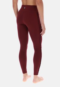 Bordowe legginsy z wysokim stanem, z teksturowanym bocznym panelem i dopasowanym krojem. Gładki materiał, bez widocznych wzorów czy logo.