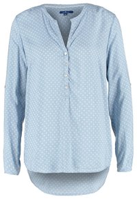 Camicia azzurra a maniche lunghe con patta abbottonata, caratterizzata da un motivo floreale e orlo asimmetrico. Realizzata in tessuto morbido e liscio.