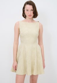 Romantische crèmekleurige jurk met bloemenpatroon, een getailleerde bodice, een uitlopende rok en een schouderdetail. Gemaakt van textuurstof, met een subtiele glans.