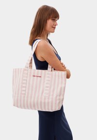 Gestreepte tote bag in roze en wit katoen, met twee stevige handvatten en geborduurd "Les Lunes" logo aan de voorkant.