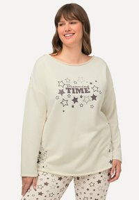 Lichtbeige lange mouw top met de tekst "Dreaming TIME" en sterpatronen. Zachte stof met een ontspannen pasvorm en brede halslijn. Gepaard met bijpassende leggings met sterrenpatroon.