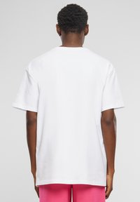 Hvid bomulds T-shirt med korte ærmer og en afslappet pasform, der har en rund halsudskæring og et enkelt design uden synlige logoer eller grafik.