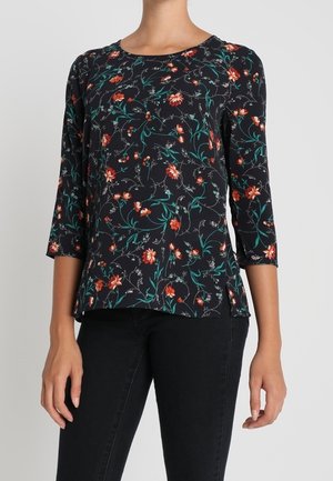 Blusa nera floreale con maniche a tre quarti. Presenta un motivo di fiori rossi e foglie verdi su uno sfondo scuro. Tessuto morbido, vestibilità rilassata.