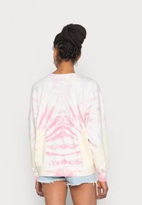 Sudadera de cuello redondo de gran tamaño en un patrón de tie-dye pastel que presenta tonos de rosa y amarillo, hecha de una suave mezcla de algodón.