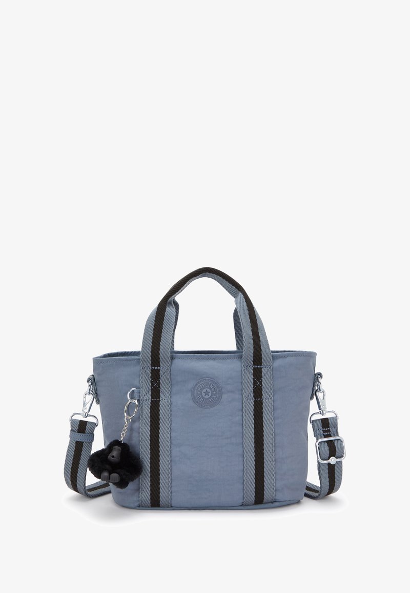 Jasnoniebieska torba materiałowa z czarnymi i szarymi paskami, okrągłym logo i przyczepionym puszystym czarnym breloczkiem w kształcie goryla.