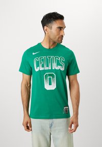 Green cotton t-shirt featuring "CELTICS" and number "0" in white text, with a Nike logo on the left shoulder and a round neckline.