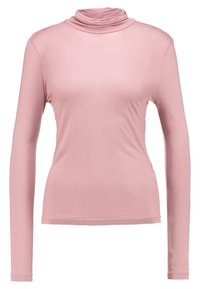 Långärmad, figurnära polotröja i mjukt, lätt rosa tyg med en slät yta och subtil drapering vid halsringningen.