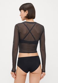 Czarna, długosleeveowa bluzka z siateczki o kroju mini oraz krzyżującymi się ramiączkami na plecach, w zestawie z czarnymi majtkami o wysokim stanie. Gładka tekstura, minimalistyczny styl.