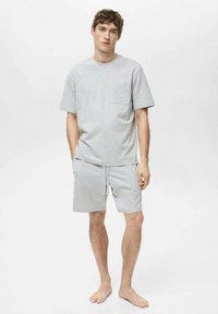 Grå bomulds t-shirt med korte ærmer og en brystlomme, parret med matchende grå shorts med elastisk talje og snore.