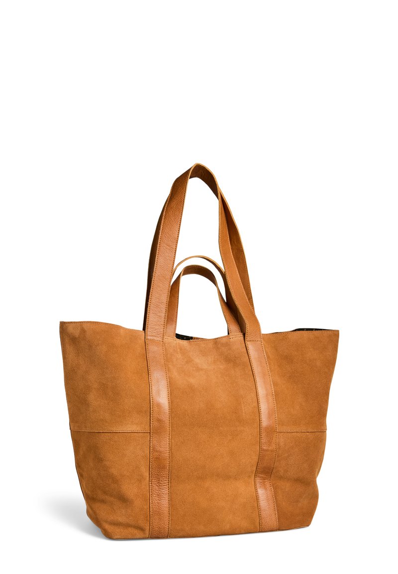 Grande sac tote en daim beige avec deux anses courtes et deux longues en cuir, se tenant debout sur un fond blanc.