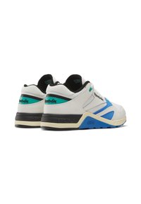 Sneakers con una toma bianca, accenti neri e blu, rete testurizzata e suola in gomma con intersuola beige e numerosi fori di ventilazione.
