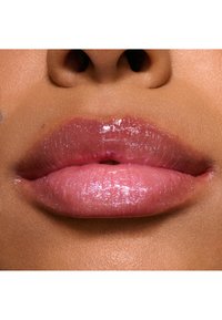 Prodotto per labbra lucido con una delicata tonalità rosa, caratterizzato da una finitura scintillante e una texture morbida. Le labbra appaiono idratate e piene.