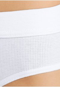 Witte katoenen onderbroek met een geribbelde textuur, een soepele tailleband en gestikte details aan de randen. Close-upweergave toont de kwaliteit van de stof.