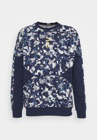 Sudadera navy con una mezcla de patrones abstractos en blanco y azul, cuello redondo, mangas largas y un pequeño logo dorado en el frente.