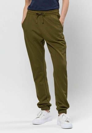Olivengrønne joggers i blødt stof med elastisk talje og snoretræk, der har sidelommer og elastiske manchetter. Sammen med hvide sneakers.