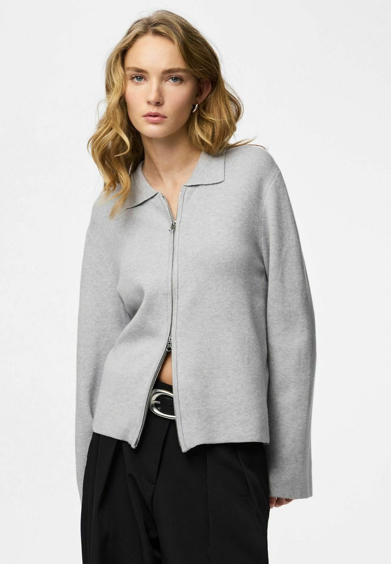 Giacca grigia chiaro con zip, collo ampio, maniche lunghe e vestibilità comoda, realizzata in materiale morbido con una texture sottile.