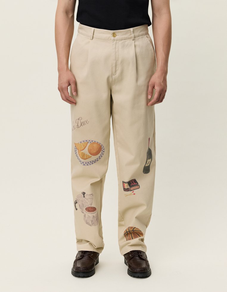 Μπεζ παντελόνια με διάφορα εικονογραφημένα τρόφιμα και ποτά, όπως μια φέτα φρούτου, καφετιέρα, μπουκάλι κρασιού και μπάλα μπάσκετ.