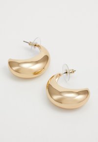 Gold-tone metal hoop earrings with a polished, smooth surface. Crescent shape with clear backing for secure wear.