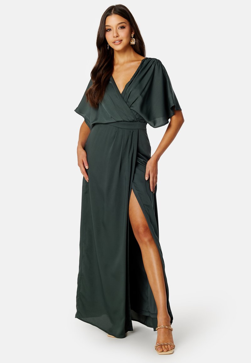 Vestito maxi avvolgente verde scuro con maniche corte a volantino, scollatura a V profonda e spacco alto fino alla coscia. Tessuto morbido e leggero con una silhouette fluida.