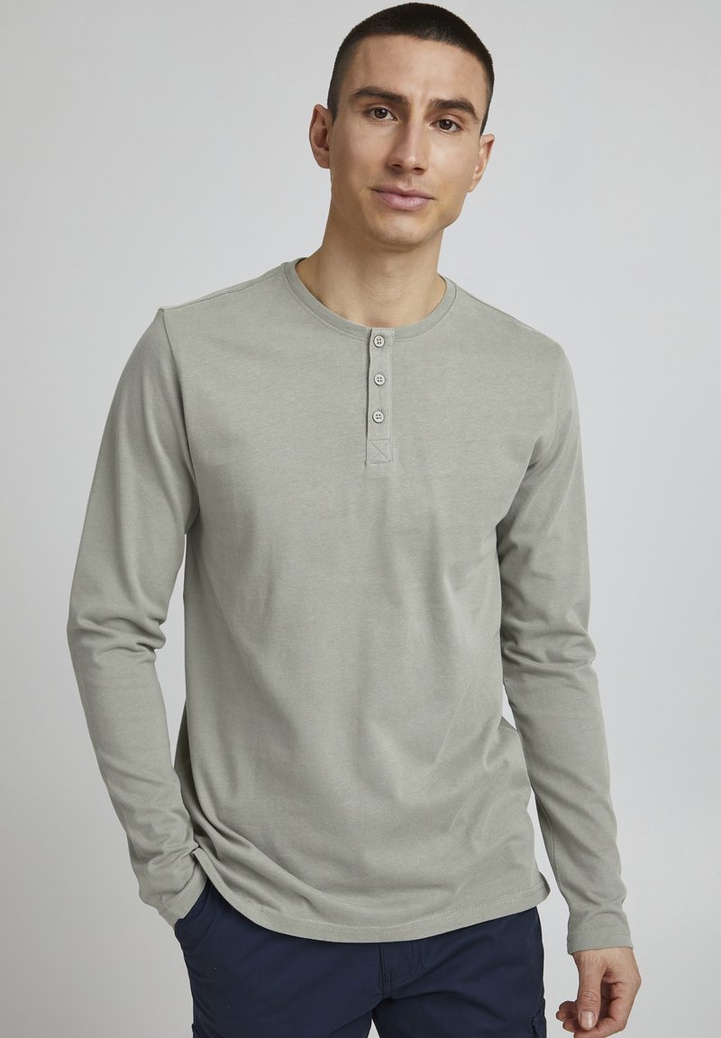 Langærmet henley skjorte i lys grå med rund halsudskæring og tre-knaps placket. Glat bomuldsstof, tætsiddende design og uden mønstre.