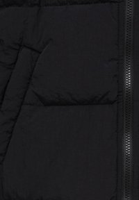 Tissu de doudoune noire avec sections matelassées et fermeture éclair à l'avant, présentant un léger éclat et une texture lisse.