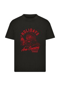 Black cotton t-shirt featuring a red graphic of Santa holding a Coca-Cola bottle with the text "Holidays Are Coming."