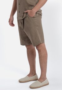 Khaki lniane szorty z kieszeniami bocznymi, luźny krój. W zestawie z kremowymi espadrylami z subtelnym wzorem w paski i jutowymi podeszwami.