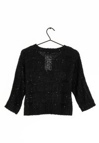 Svart tröja med lös passform, långa ärmar, ribbat slag och strukturerat mönster. Har subtila glittrande inslag i tyget.