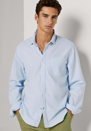 Lichtblauw overhemd met knopen, gemaakt van katoen, met een borstzak, lange mouwen en een licht gebogen zoom. Het materiaal heeft een gladde textuur.