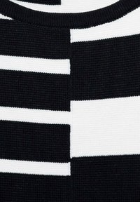 Top lavorato a maglia con un motivo a righe nere e bianche di diverse larghezze. Texture a coste e scollatura rotonda.